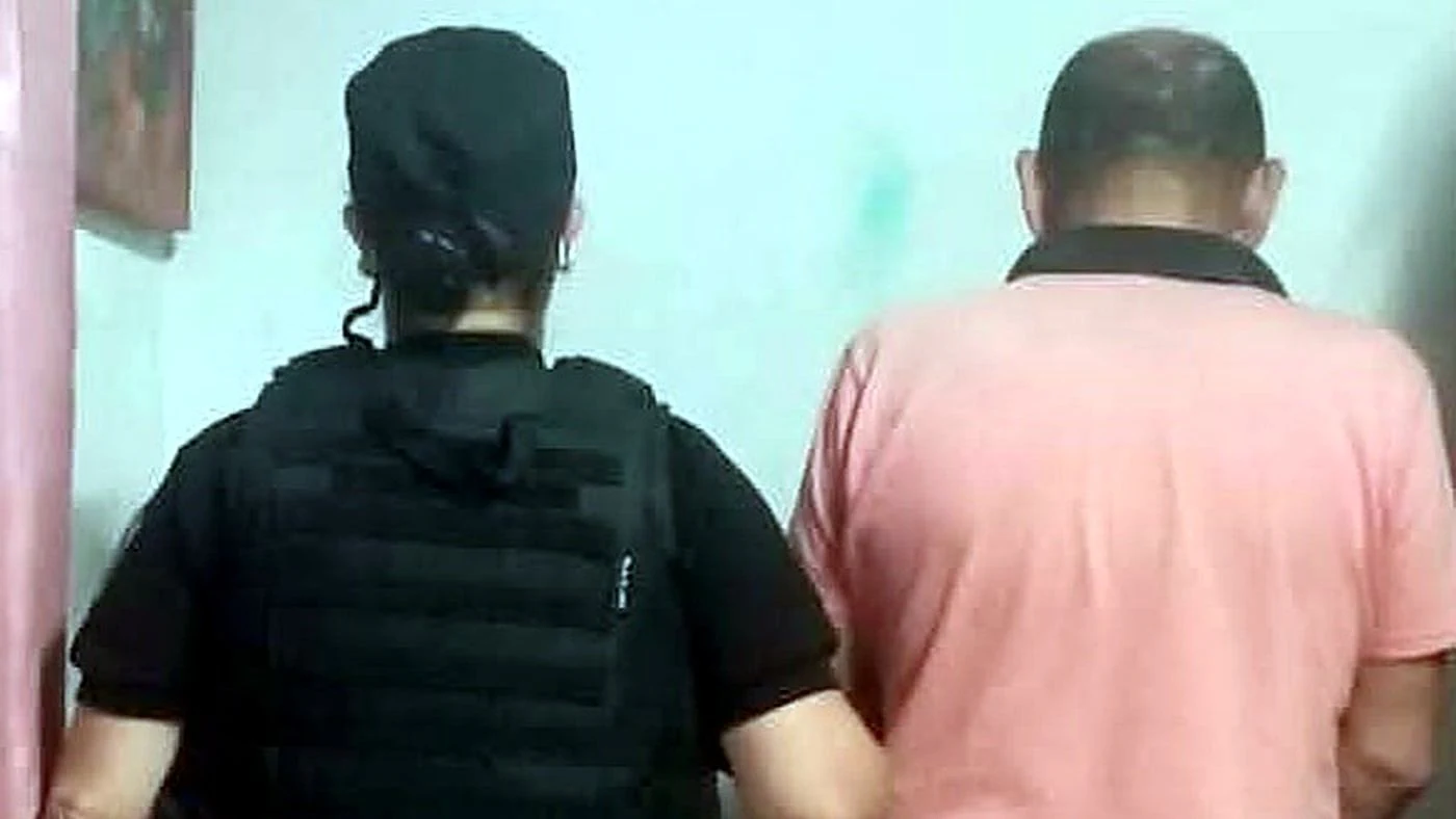 Una agente policial acompaña de espaldas al hombre aprehendido en San Cristóbal por violar una prohibición de acercamiento